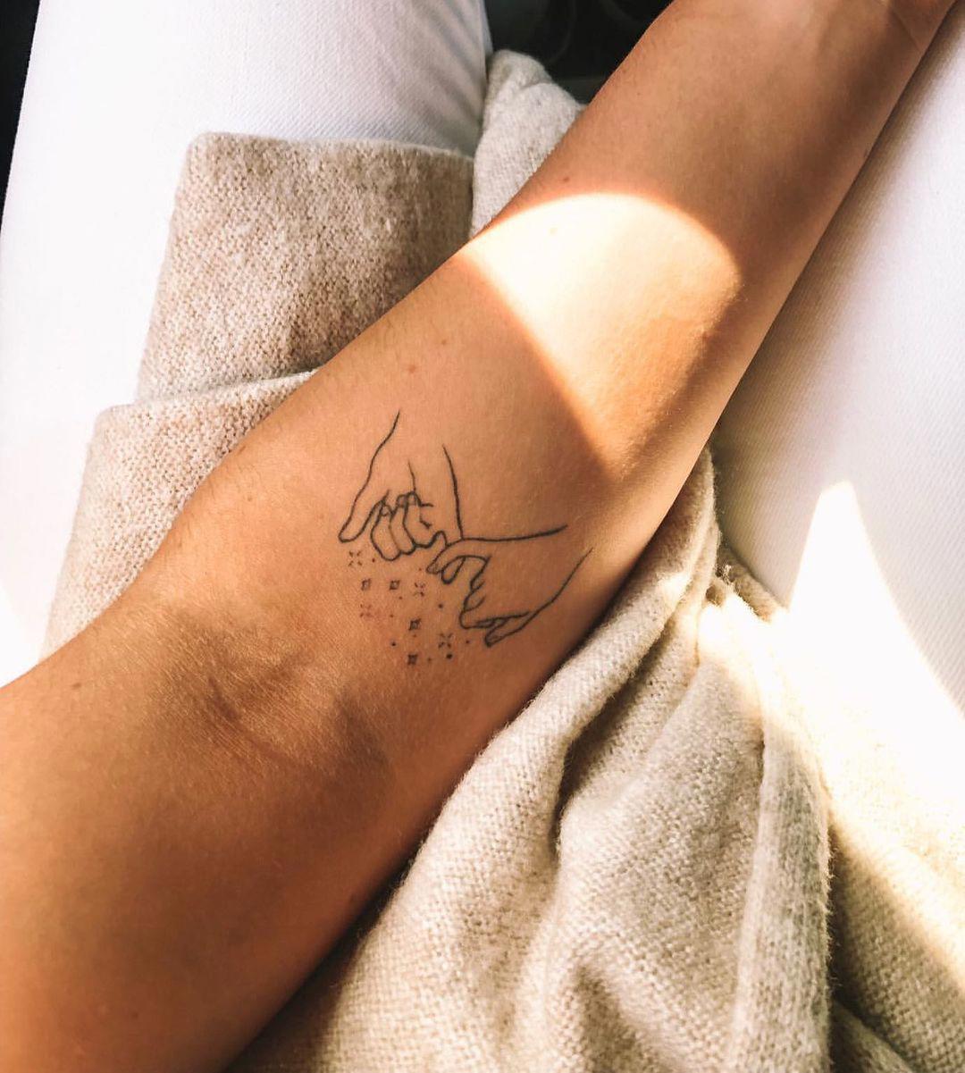 Tatuaje de manos dadas en el antebrazo